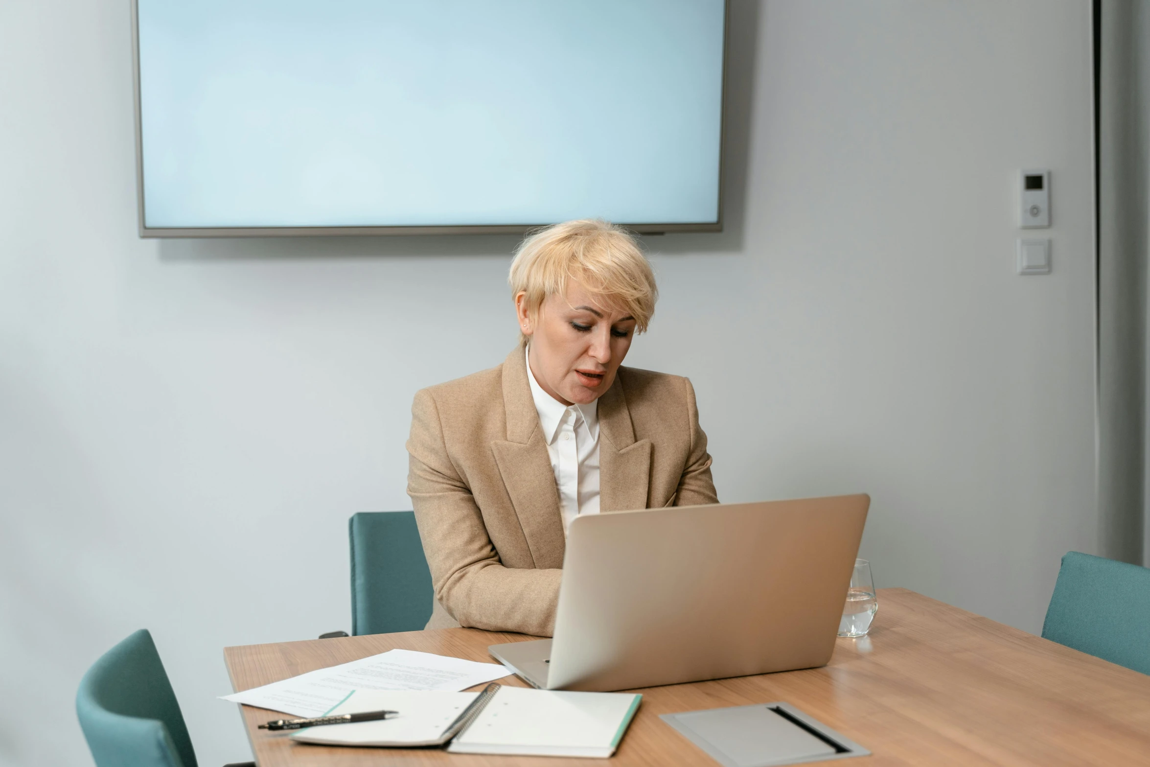 a woman sitting at a table with a laptop computer, in a meeting room, slightly minimal, lachlan bailey, white haired lady