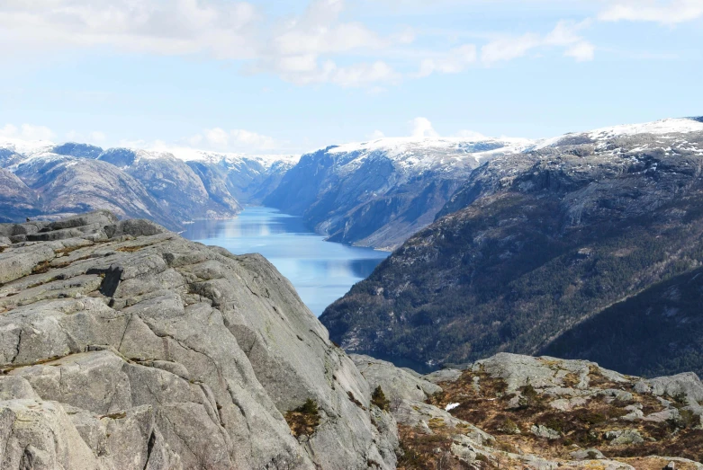 a man standing on top of a mountain next to a body of water, by Tom Wänerstrand, pexels contest winner, hurufiyya, snowy fjord, a photo of a lake on a sunny day, slide show, huge chasm