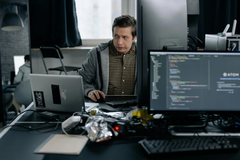 a man sitting at a desk in front of a computer, by Adam Marczyński, pexels, covered in circuitry, casually dressed, lachlan bailey, server in the middle