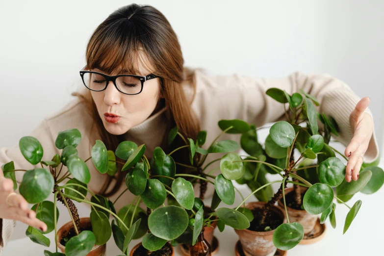 a woman holding a bunch of potted plants, trending on pexels, wearing black rimmed glasses, avatar image, smelling good, top down photo