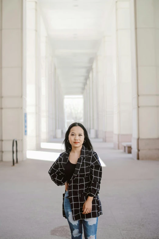 a woman standing in the middle of a hallway, inspired by Wang E, unsplash, on a large marble wall, with black hair, in a city square, phong shaded