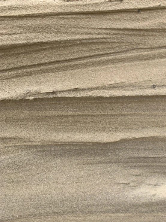 a man riding a surfboard on top of a sandy beach, a picture, inspired by Kay Sage, tonalism, stylized stone cladding texture, taupe, closeup - view, detailed wood