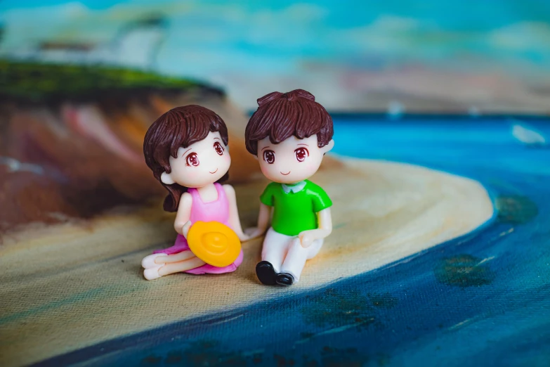 a couple of figurines sitting on top of a sandy beach, pexels contest winner, polymer clay earrings, cute cartoon style, boy girl traditional romance, a high angle shot
