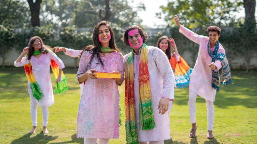 a group of people standing on top of a lush green field, a portrait, shutterstock, color field, wearing festive clothing, wearing a kurta, face painting, ( ( ( colorful ) ) )