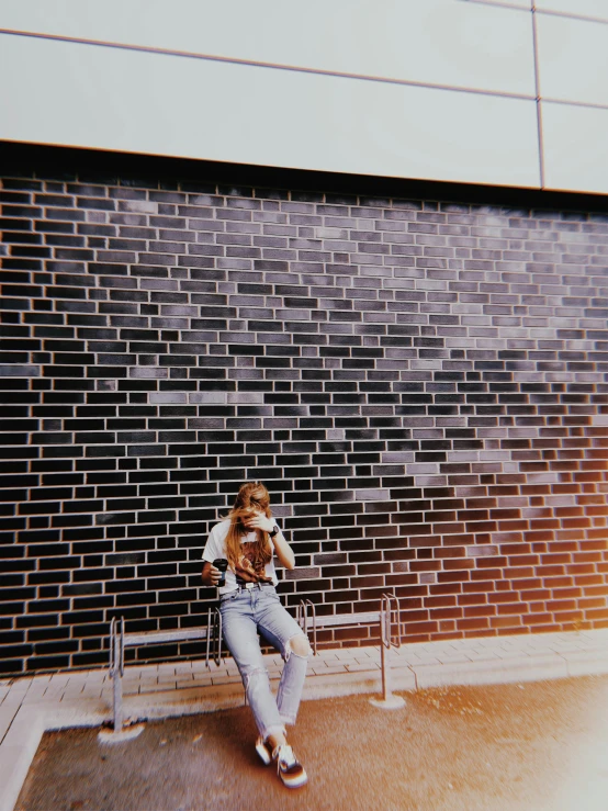 a man sitting on a bench in front of a brick wall, by Lee Gatch, unsplash, vhs effect, the girl plays the guitar, taking a picture, sittin