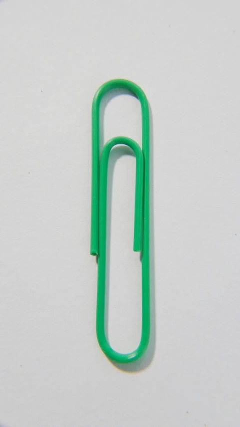 a green paper clip sitting on top of a white surface, by Nassos Daphnis, hanging, 2 0 1 4, 105mm, josh grover