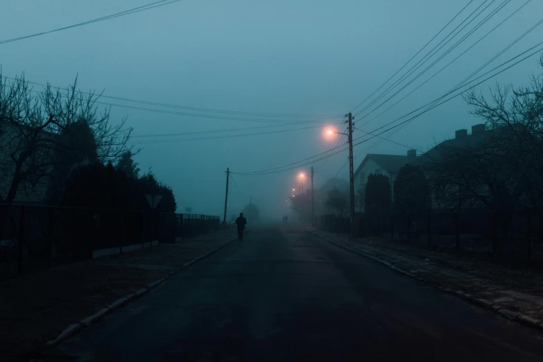 a person walking down a street at night, inspired by Elsa Bleda, pexels contest winner, postminimalism, pale blue fog, in a suburb, overcast dawn, magical soviet town