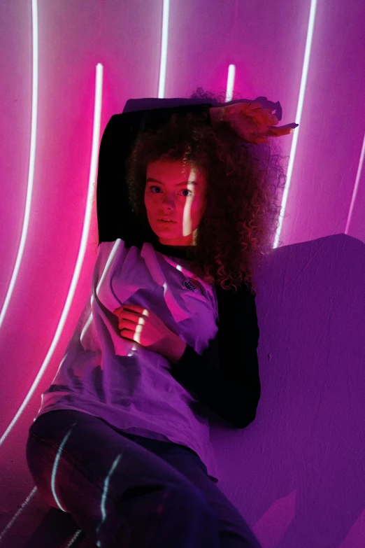 a woman laying on top of a purple couch, interactive art, fashion neon light, curly haired, photograph of a techwear woman, low quality photo
