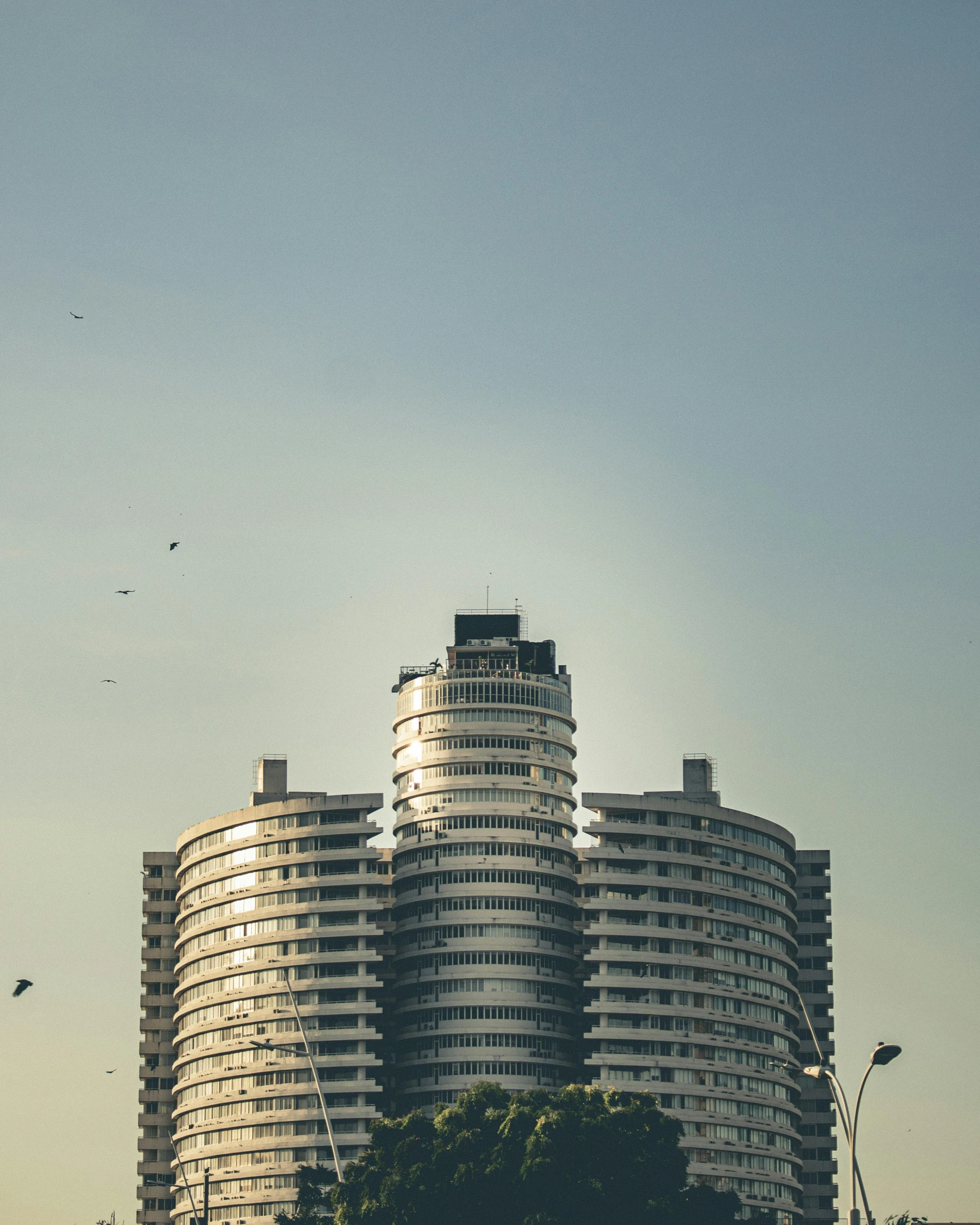 a group of people flying kites in front of a tall building, unsplash contest winner, brutalism, hotel room, warsaw, rounded architecture, colombo sri lanka cityscape