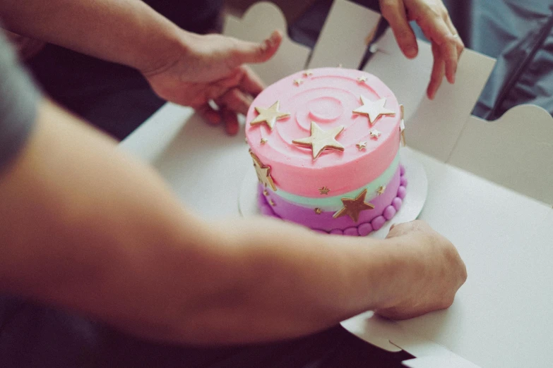 a close up of a person cutting a cake in a box, a colorized photo, by Julia Pishtar, pexels contest winner, seven pointed pink star, minecraft cake, retro effect, foil