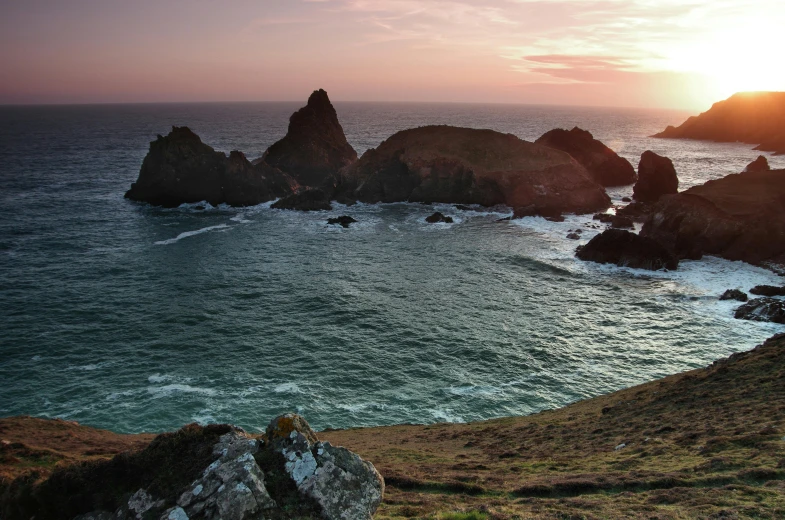 a large body of water sitting on top of a lush green hillside, an album cover, by Peter Churcher, pexels contest winner, which shows a beach at sunset, devils horns, pembrokeshire, thumbnail