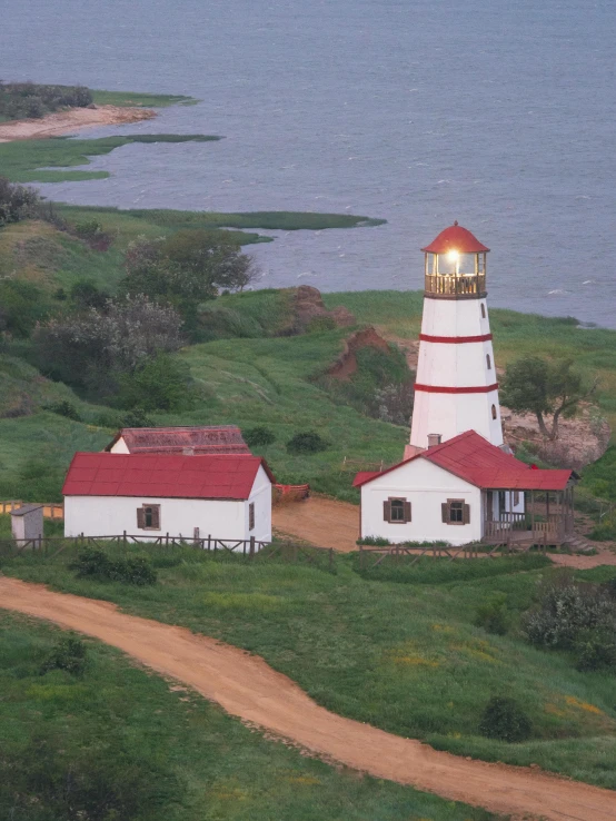 a lighthouse sitting on top of a lush green hillside, hziulquoigmnzhah, lit from above, set photo