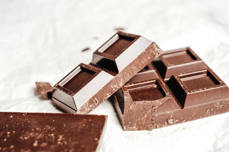 a couple of pieces of chocolate sitting on top of a table, trending on pexels, private press, black squares on 4 corners, 6 pack, white background, magnesium