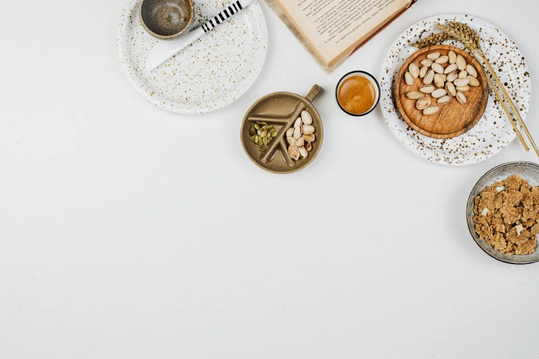 a table topped with plates of food next to an open book, a still life, inspired by Ceferí Olivé, trending on pexels, private press, white minimalistic background, moroccan tea set, gravel and scree ground, background image