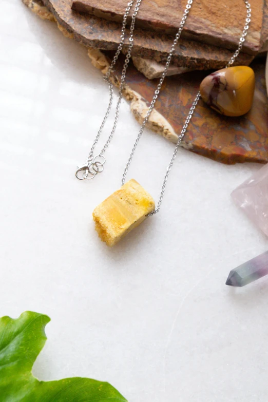 a piece of cheese sitting on top of a wooden cutting board, inspired by Luma Rouge, unsplash, gemstone necklace, yellow, modeled, ashes crystal