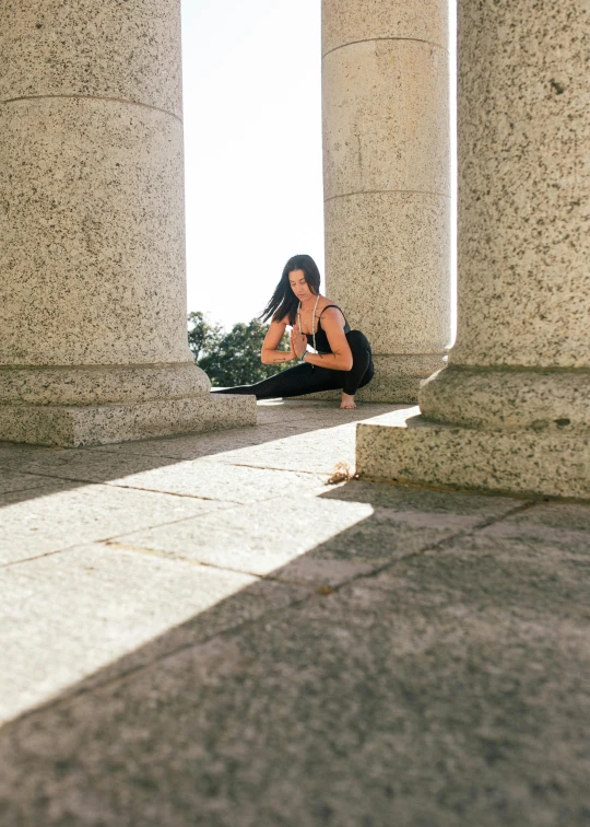 a woman sitting on the ground talking on a cell phone, a marble sculpture, by Nina Hamnett, pexels contest winner, pillars and arches, yoga pose, natural light outside, spanish