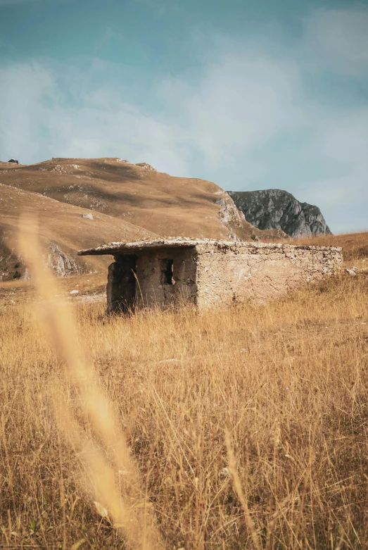 a stone building sitting on top of a dry grass covered field, by Muggur, unsplash contest winner, renaissance, 1960s color photograph, limestone, hut, italy