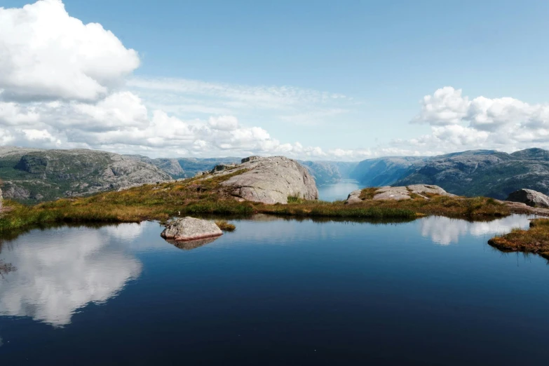 a body of water sitting on top of a lush green hillside, by Jesper Knudsen, pexels contest winner, hurufiyya, norwegian, infinity pool mirrors, thumbnail, conde nast traveler photo