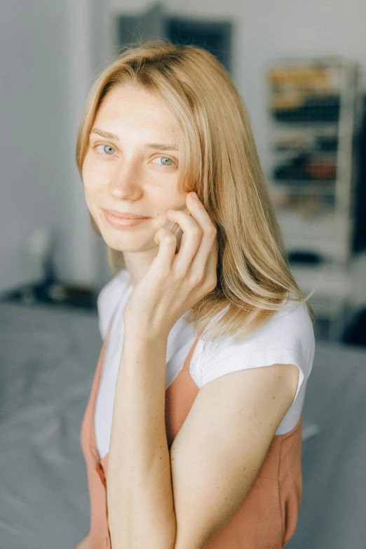 a beautiful young woman sitting on top of a bed, a character portrait, reddit, close up of a blonde woman, hand on cheek, low quality photo, nadezhda tikhomirova