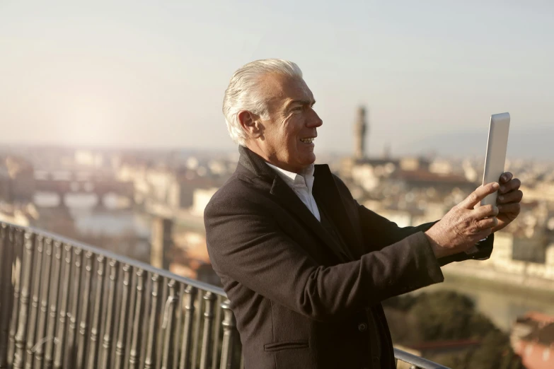 a man taking a picture with his cell phone, by Giuseppe Avanzi, happening, older male, with a city in the background, slide show, portrait image