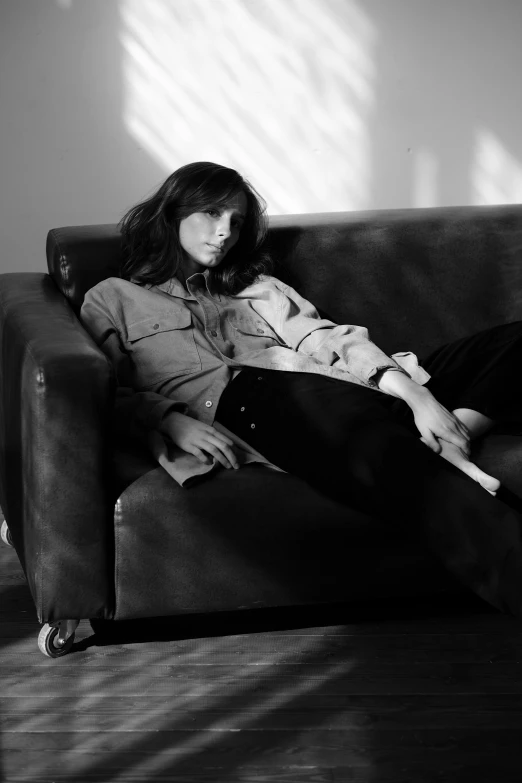 a black and white photo of a woman sitting on a couch, photorealism, curtain bangs, she wears a jacket, sprawled out, promo image