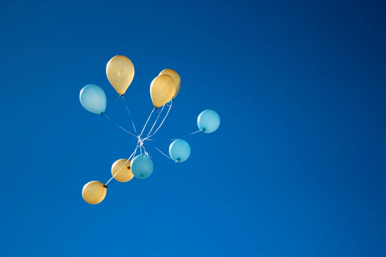 a bunch of yellow and blue balloons floating in the air, unsplash, cloudless-crear-sky, shot on sony a 7, light-blue, celebrating a birthday