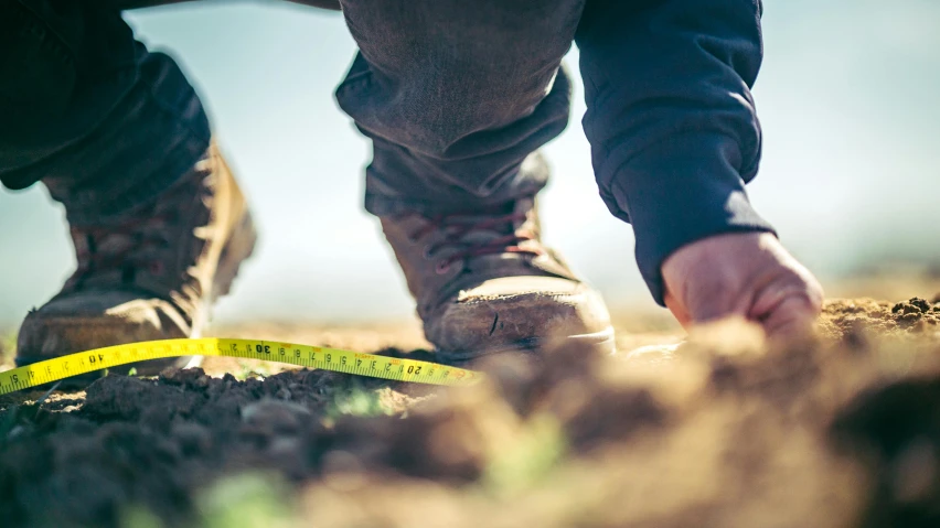 a close up of a person's feet with a measuring tape, a photo, pexels contest winner, renaissance, soil landscape, people at work, shallow depth of fielf, portrait of tall