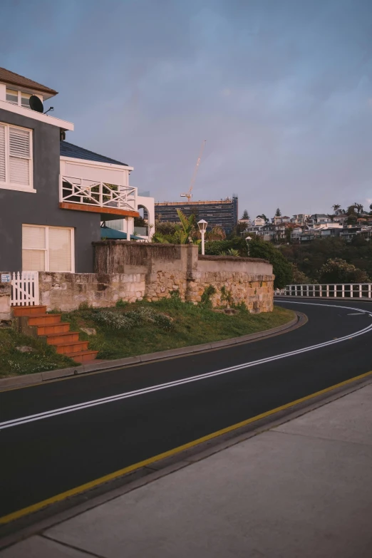 a house sitting on the side of a road, unsplash, photorealism, south african coast, 90's photo, city scape, late summer evening