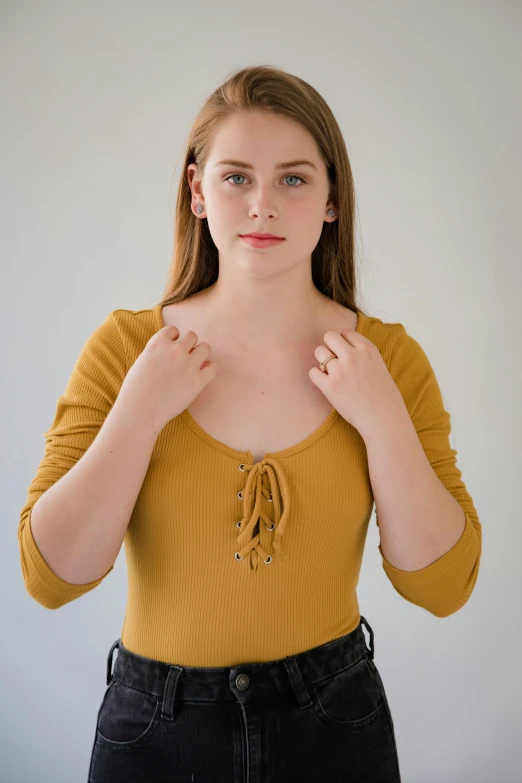 a woman in a yellow shirt posing for a picture, inspired by Claire Dalby, shutterstock contest winner, renaissance, muted colored bodysuit, beautiful well rounded face, sydney sweeney, long sleeves