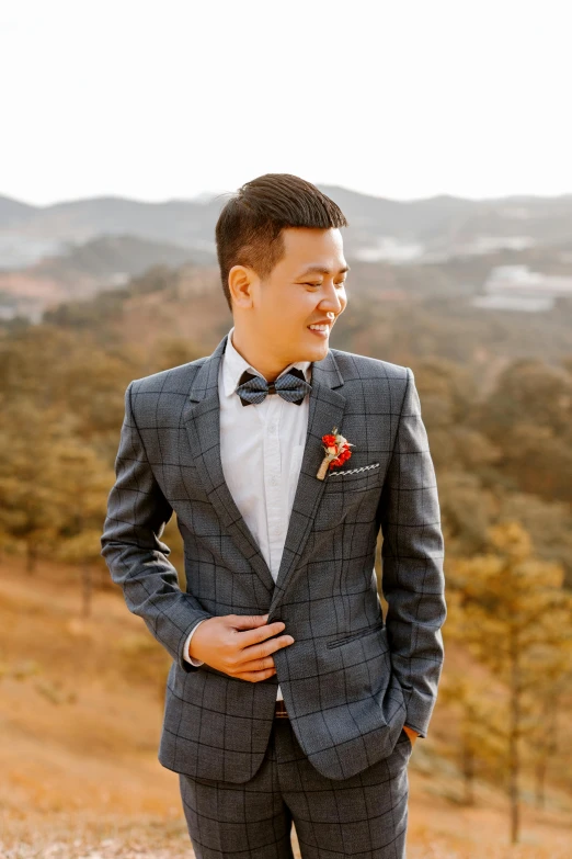 a man in a suit standing in a field, a colorized photo, inspired by Joong Keun Lee, unsplash, groom, hills in the background, bow tie, asian features
