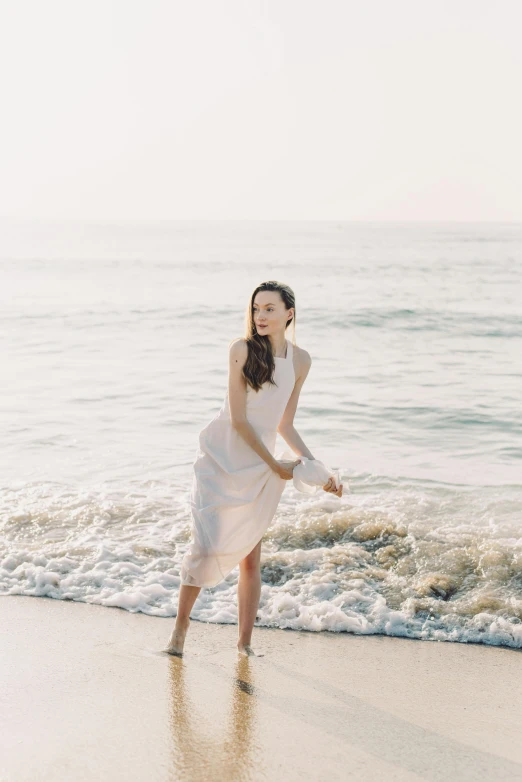 a woman standing on top of a beach next to the ocean, wearing organza gown, pale fair skin, lulu chen, barefoot in sandals