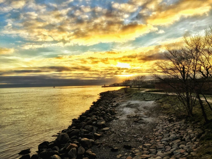 the sun is setting over a body of water, by Jan Tengnagel, pexels contest winner, rocky shore, scenic view of river, oland, enhanced photo