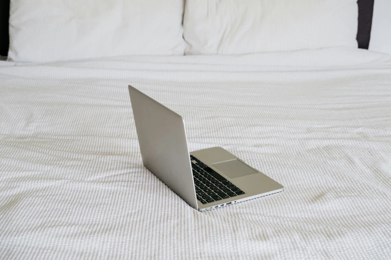 a laptop computer sitting on top of a bed, by Carey Morris, white metallic, small