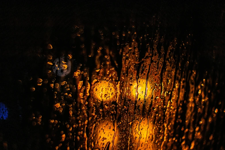 a close up of a rain covered window at night, art photography, liquid gold, atmospheric lighting - n 9, streetlamps with orange light, golden orbs and fireflies