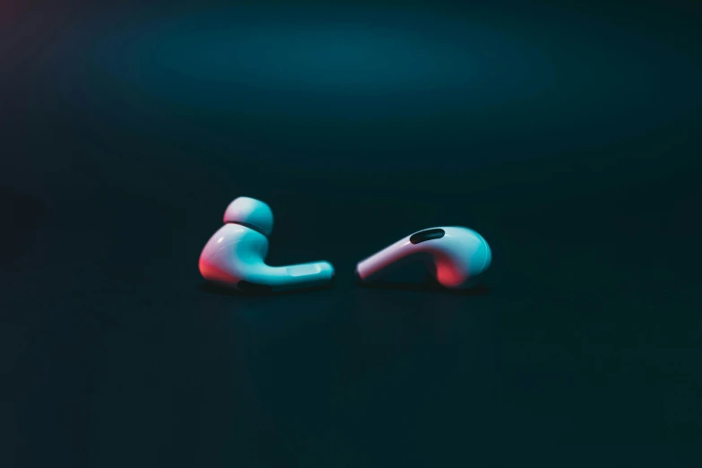 a pair of earphones sitting on top of a table, by Filip Hodas, trending on pexels, digital art, red and cyan, airpods, with a black background, news