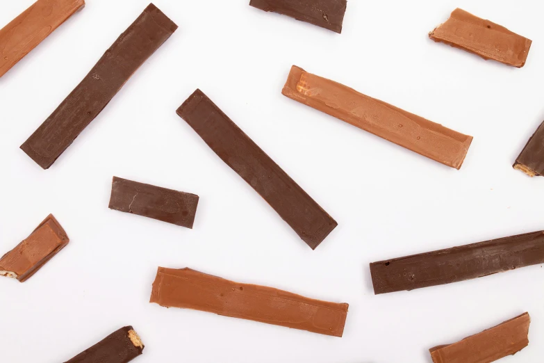 a group of pieces of chocolate sitting on top of a white surface, jackstraws, detailed product image, slate, black and brown