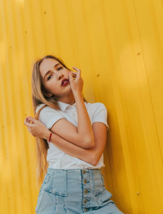a woman leaning against a yellow wall talking on a cell phone, trending on pexels, aestheticism, dslr photo of a pretty teen girl, her belly button is exposed, primary colors are white, lalisa manobal