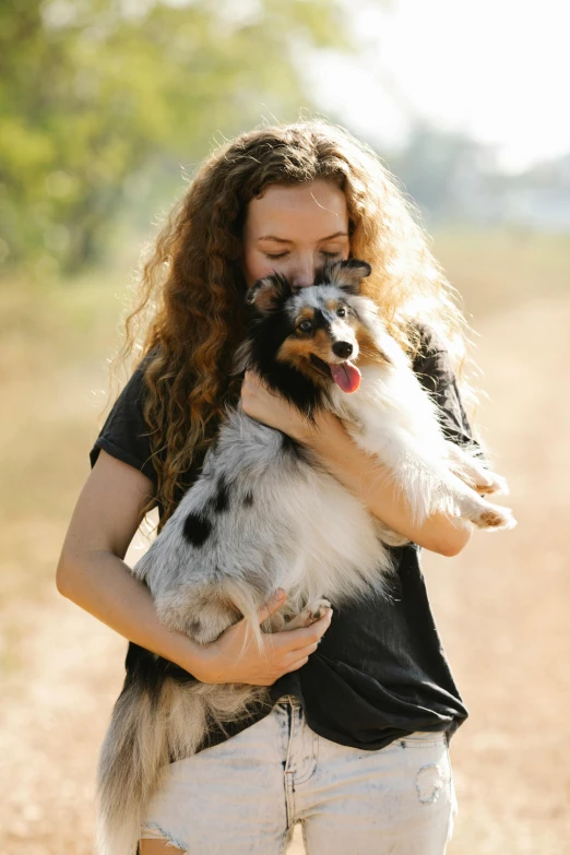 a woman holding a dog on a dirt road, profile image