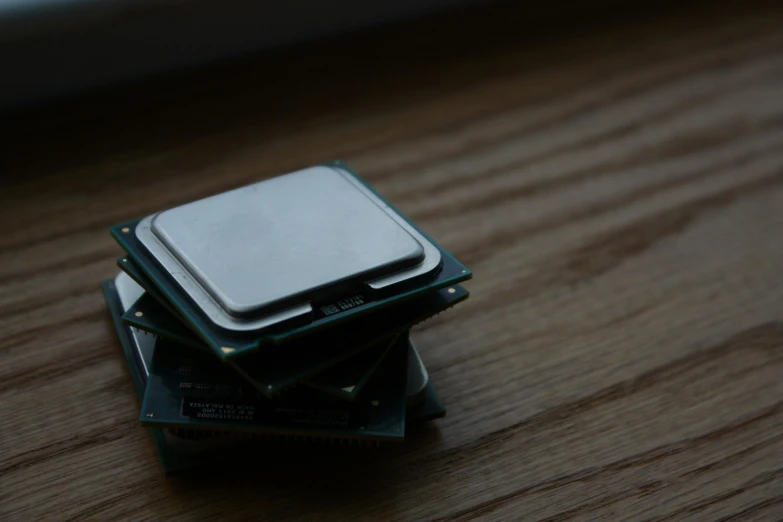 a computer processor sitting on top of a wooden table, unsplash, stacks, steam workshop, low quality photo, grey