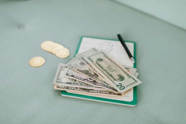 a pile of money sitting on top of a pile of coins, by Matt Cavotta, trending on unsplash, on a notebook page, pastel green, cash on a sidetable, 1970s photo