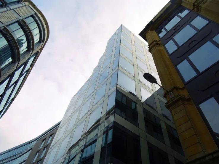 a tall building with a street light in front of it, a photo, inspired by Richard Wilson, unsplash, with shiny glass buildings, square, wellington, taken in the 2000s