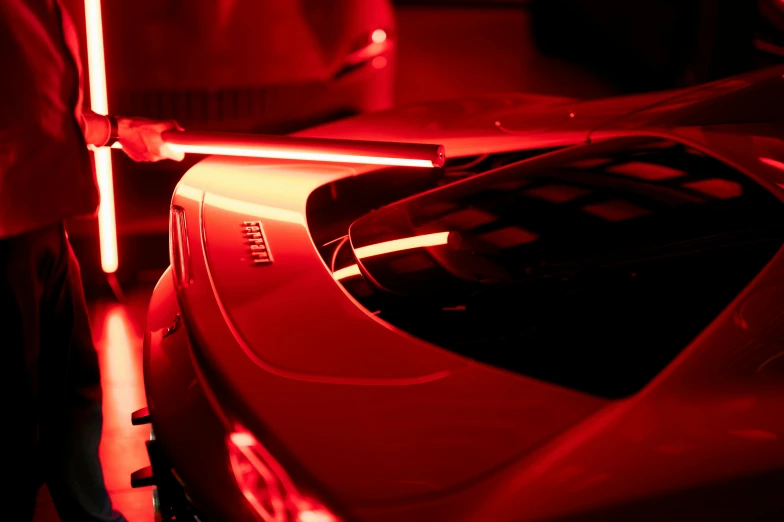 a man standing next to a red car, inspired by Elsa Bleda, unsplash, led light strips, sports car in the room, closeup photograph, redshift. micro details