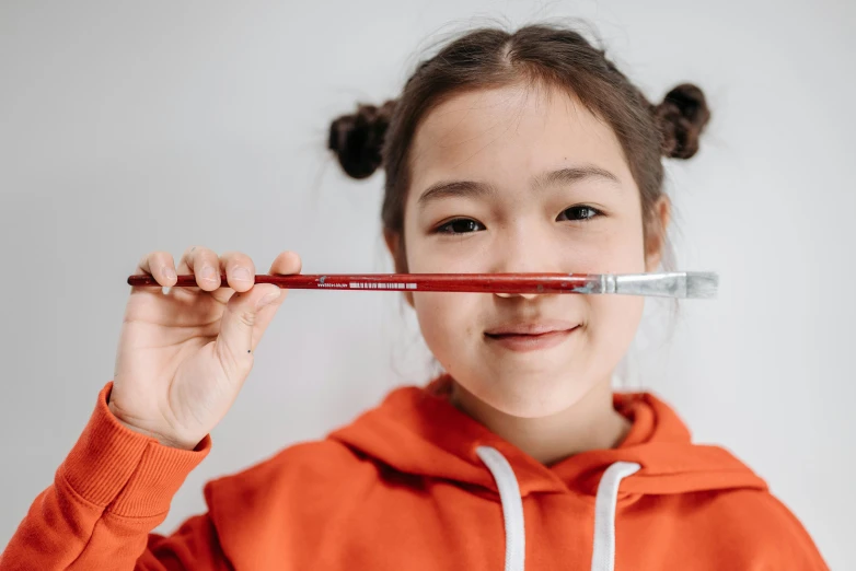 a little girl that is holding a toothbrush in her mouth, a hyperrealistic painting, pexels contest winner, hyperrealism, jazza and rossdraws, red ballpoint pen, product introduction photo, holding a crowbar