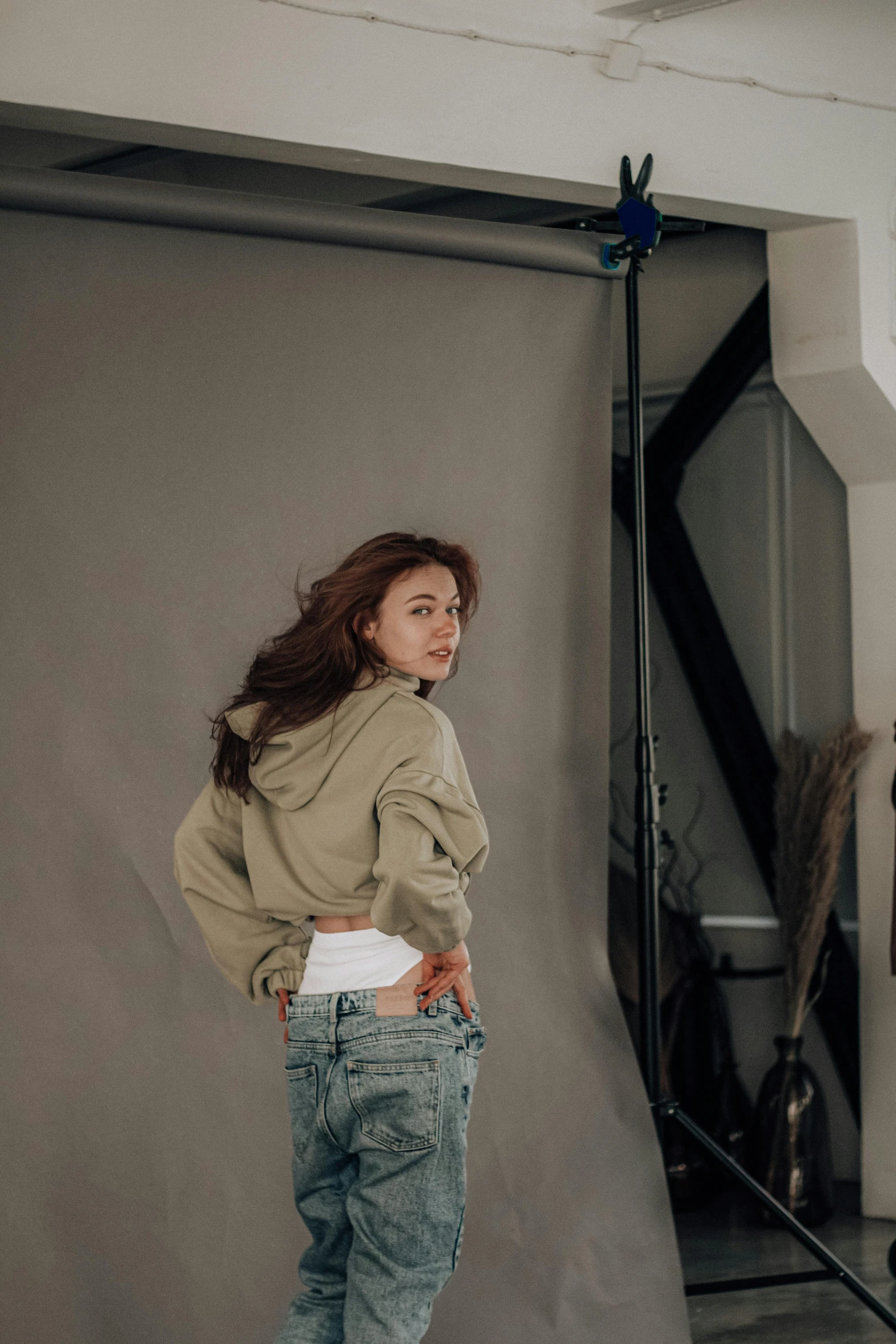 a woman that is standing in front of a camera, trending on pexels, photorealism, wearing jeans and a black hoodie, wavy hair spread out, vs studio, photo studio