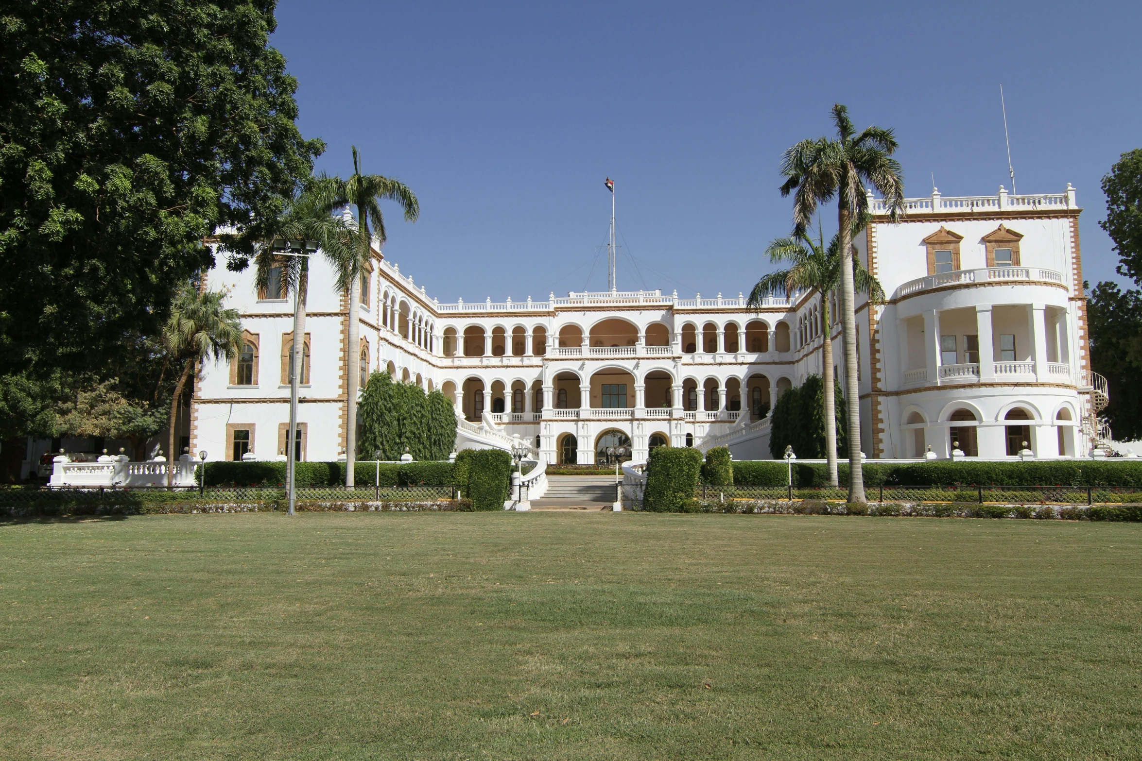 a large white building sitting on top of a lush green field, inspired by Sardar Sobha Singh, in balcony of palace, oman, schools, the white house