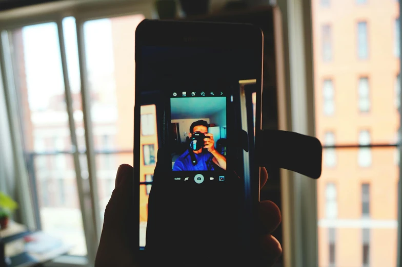 a person taking a picture with a cell phone, by Robbie Trevino, unsplash, video art, lofi portrait at a window, android close to camera, rectangle, shot on sony a 7