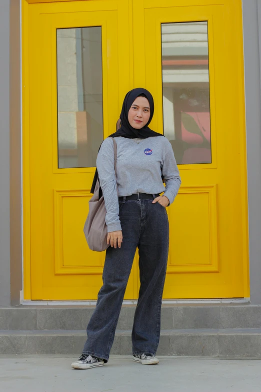 a woman standing in front of a yellow door, inspired by Naza, instagram, hurufiyya, wearing jeans and a black hoodie, blue and grey theme, 8 k ), monochrome!!!!!