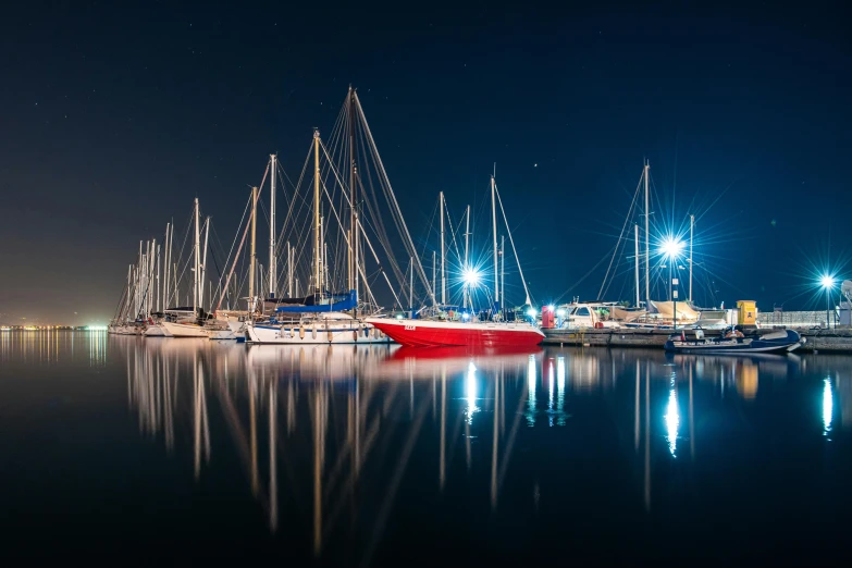 a bunch of boats that are sitting in the water, by Adam Marczyński, pexels contest winner, reflective lighting, red and blue reflections, three masts, thumbnail