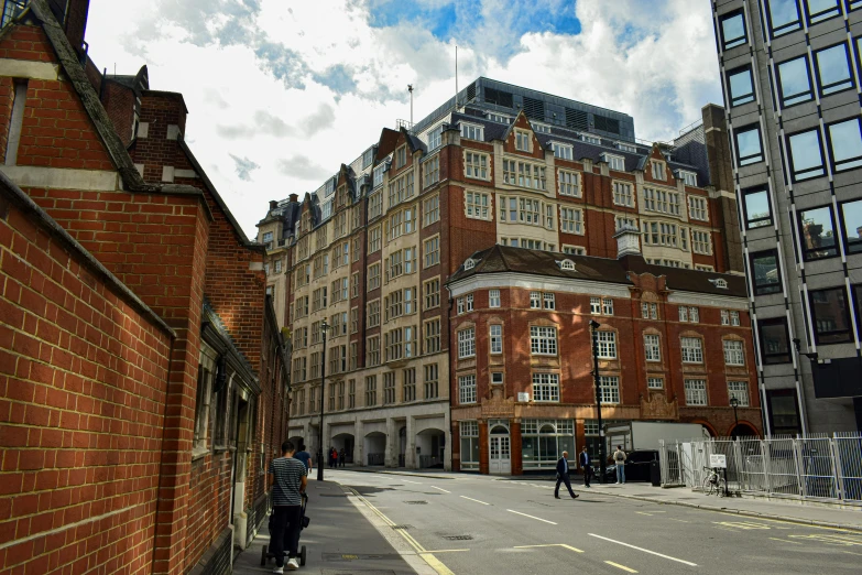 a man riding a skateboard down a street next to tall buildings, by Anna Findlay, unsplash, art nouveau, brick building, 1 9 th century london, square, 2000s photo