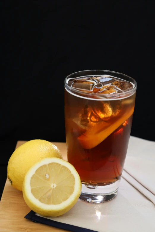 a drink sitting on top of a cutting board next to a lemon, tall iced tea glass, on black background, f / 2. 8, cold brew coffee )